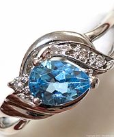 Front view of pear-cut blue topaz in 14K white gold setting with diamond accents