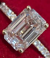 Close-up of emerald-cut center lab diamond in four-prong yellow gold setting