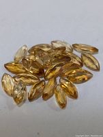 Close-up photo of multiple marquise-cut citrine loose gemstones arranged on a white background, showing their yellow-orange color and faceted surfaces.