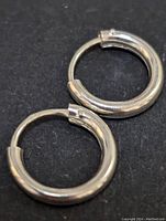 Photo showing two silver hoop earrings laid flat to display shape and clasp detail.