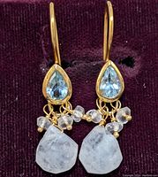 Front view of earrings showing blue topaz teardrop shape and dangling moonstone and beads.