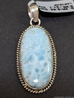 Front view of the oval Larimar pendant showing the light blue gemstone with white marbling and detailed silver rope border.