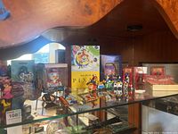 Display cabinet shelf with assorted Disney memorabilia including figurines, books, postcards and collectible items.