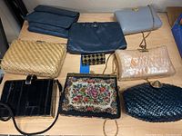 Seven vintage handbags and clutches displayed together showing variety in materials and styles.