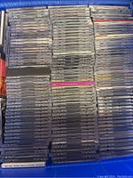 Top view of a large box filled with numerous CDs in jewel cases arranged in stacks.