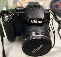 Front view of the Nikon Coolpix P500 camera showing the Nikon logo and lens cap.