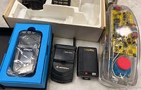 Mixed lot of communication devices including boxed Samsung phone, Motorola flip phone, Panasonic pager, and electronics kit.