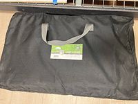 Closed black canvas carry bag with grey shoulder straps and REI Camp Kitchen label on front