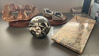 Image showing entire lot on table, including the black and white orb, geode halves on bases, petrified rock with holes, and pedestal slab