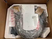 Vacuum components packed in molded white styrofoam inside damaged cardboard box; hose and attachments wrapped in plastic.