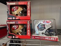Three mini helmets displayed on wire shelving