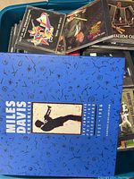 Photo showing a blue tub filled with various CDs including a large Miles Davis Chronology boxed set and other jazz and easy listening albums.