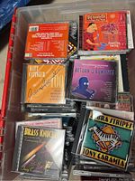 Top view of a plastic tub filled with jazz and big band swing CDs, showing titles like Matt Catingub Orchestra and Tony Caramia.