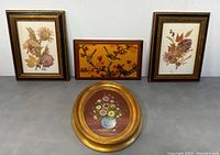 Four framed artworks displayed together: two rectangular pressed flower artworks, one rectangular bird artwork, one oval flower painting.