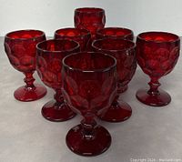 Front and side view of all 8 Viking Glass ruby red goblets arranged in a group, showing the color and design details.