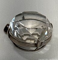 Close-up view of the clear, cushion-cut faceted quartz stone in the silver setting from front angle.