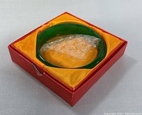 Natural green jade bangle inside original red box lined with yellow fabric, showing slight damage to box corner.