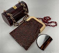 Overview photo showing the metal mesh bag, lucite box clutch, and tortoiseshell comb arranged on a white surface.