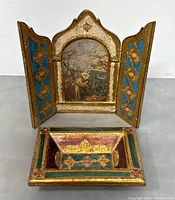 Shows the Florentine icon triptych fully opened with visible religious painting and the matching Florentine ashtray in front.