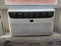 Front view of first Frigidaire window air conditioner unit installed in window, showing control panel and vents.