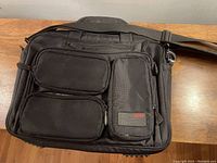 Front view of the black Mobile Edge laptop bag showing three zippered compartments and a shoulder strap.