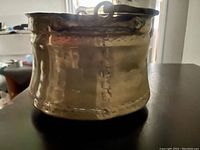 Side front view of worn mid-18th century copper bowl showing hand-forged seams and patina.