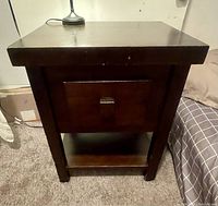 Front view of the dark wood side table showing drawer and lower shelf.