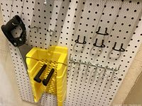 White pegboard with various hooks, yellow organizer holding screwdrivers and metal hooks attached.