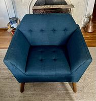 Top front view of blue wide lounge chair showing button tufted seat and back cushions, and wooden angled legs in pecan finish.