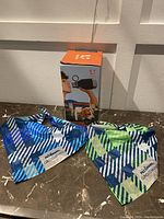 Dog water bottle in box with two geometric patterned bandanas on marble surface