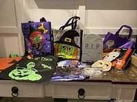 Photo of the Halloween treat bags, faux gravestone, pumpkin carving tools, and assorted Halloween decorations arranged on a countertop.
