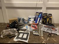 Photo showing various household and electrical items including protective glasses, screwdrivers, coil cords, outlets, zip ties, and other tools.