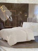 Photo of the bed styled with the white shaggy comforter, showing the plush texture and matching pillows on a bed in a staged room.