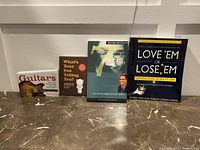 Four books laid out against a white wall; titles about guitars, health, nonprofit success, and employee engagement
