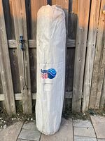 White cylindrical bubble cover packaging standing upright against a wooden fence outdoors, showing Club Pro logo.