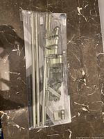 Image shows packaged new curtain rod set and mounting hardware on a marble floor.