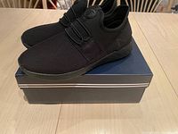 Pair of new black Nautica shoes on navy shoe box, showing side view and elastic laces.