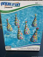 Box showing six colorful party hat floating targets in a pool with three yellow rings for tossing.