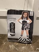 Packaged Ra Ra Rebel costume with image of child model wearing costume, showing style and pieces included