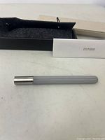 22 Studio pen placed on a surface alongside a black felt case and a cream-colored cardboard box with 22 Studio branding visible on the box and a small card.