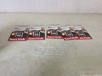 Photo showing all five packaged SanDisk memory cards and their protective cases laid out on table.