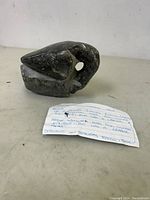 Close-up photo of the stone carving showing the abstracted goose form and hole for the eye on a white surface.