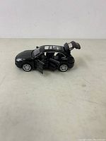 Side view of black Porsche Cayenne collectible model with open front and rear doors showing interior details.