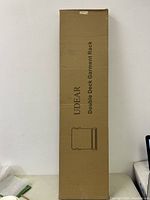 Photo of the UDEAR branded cardboard box packaging showing the label 'Double Deck Garment Rack' and line drawing of the rack.