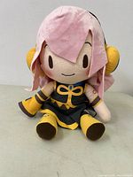 Front view of the plush showing pink hair, facial features, and full yellow and black outfit details.