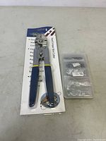 Hand crimper wire cutter tool packaged in blister pack next to plastic organizer box with wire connectors.