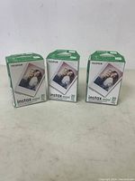 Three unopened boxes of Fujifilm Instax Mini instant film, each labeled for 20 exposures, placed side by side on a plain surface.