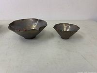 Two Joseph clay art bowls with ladybugs visible on rims, bronze finish, textured surface.
