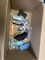 Top view of a box showing multiple eyeglasses cases in various colors alongside eyeglass frames and smaller items in packaging.