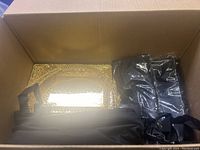 View inside box showing decorative golden trays and black bags.